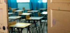 Aula vacía con escritorios desordenados.